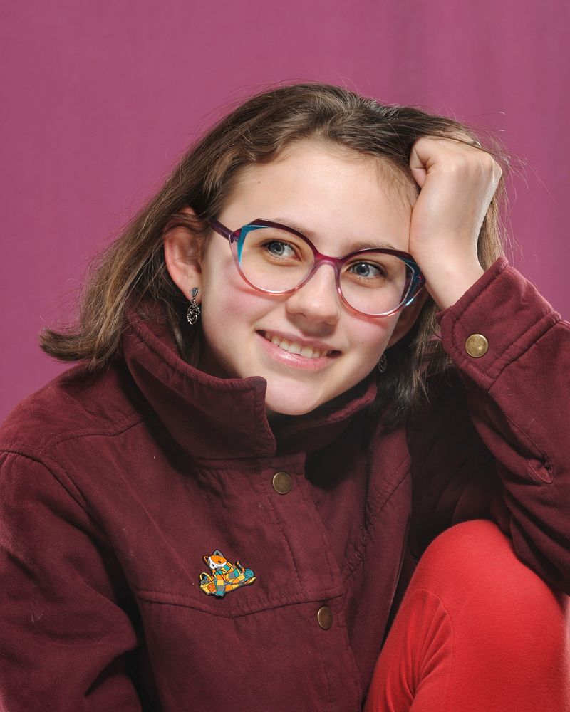A smiling young patient of The Optical Centre in pink and blue frames